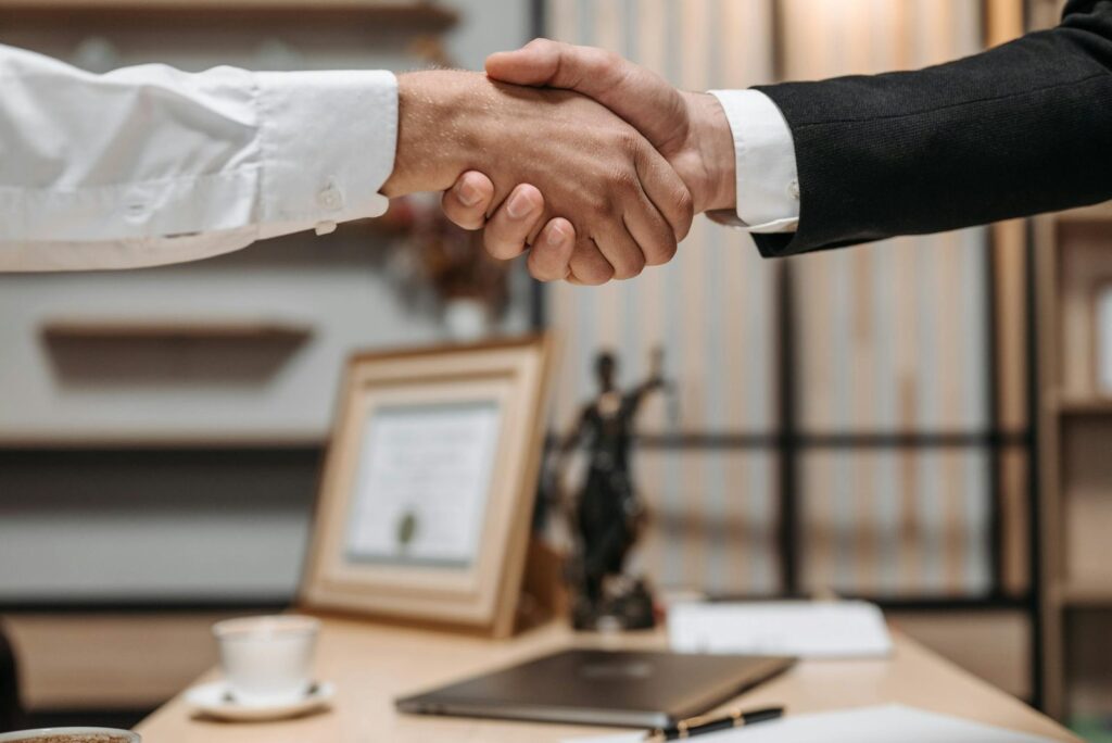 Pen on signed paperwork with handshake background